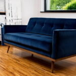 Granatowa sofa dwuosobowa stoi w salonie