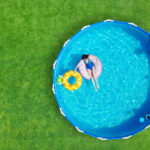 Kobieta pływa w basenie stelażowym w ogrodzie